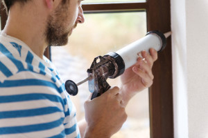 Man applying silicone sealant with caulking gun